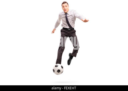 Studio shot of a young businessman kicking a football shot in mid–air isolated on white background Stock Photo