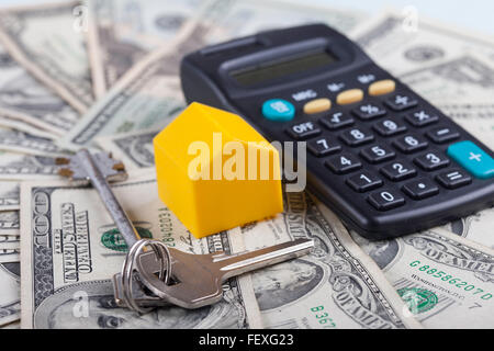 toy house, keys and calculator on the background dollars banknotes Stock Photo