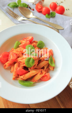 Penne pasta with bolognese sauce with fresh basil on white plate