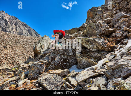 Hiking. Woman with a backpack gently descends on large boulders . Mountains of Eastern Siberia Stock Photo