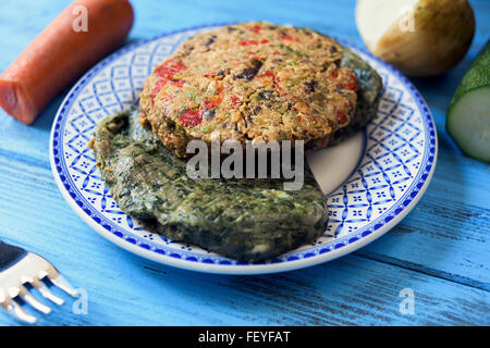 closeup of some different veggie burgers in a ceramic plate, on a rustic blue wooden table Stock Photo