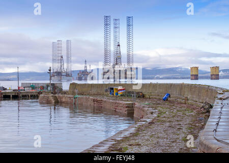 CROMARTY HARBOUR WALLS WITH NORTH SEA OIL RIGS ANCHORED IN THE FIRTH BLACK ISLE SCOTLAND Stock Photo