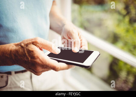 Senior man next to the window using smartphone Stock Photo