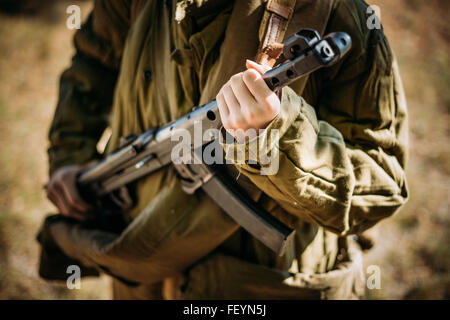 Unidentified woman reconstructor dressed as a Soviet military soldier with a submachine gun in hand. Close up on hands Stock Photo