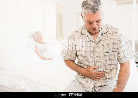 Suffering senior man holding his belly Stock Photo