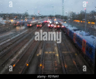 A dreary, rainy winter view of commuter trains through a wet window Stock Photo