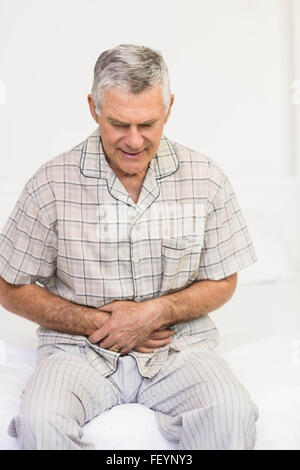 Suffering senior man holding his belly Stock Photo