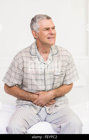 Suffering senior man holding his belly Stock Photo