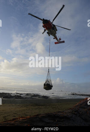 A Coast Guard Air Station Astoria-based MH-60 Jayhawk helicopter crew lifts a net full of beach debris and trash from a beach near Neah Bay, Wash., Jan. 22, 2016. More than four helicopter trips were made to help clear the beach of plastic and other forms of trash. Stock Photo