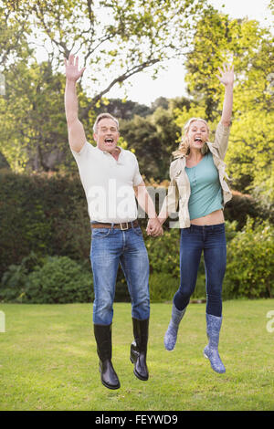 Cute couple jumping with arms in the air Stock Photo