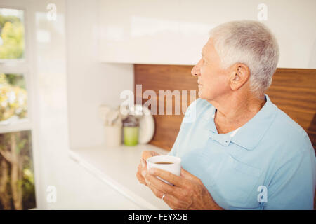 Senior man holding cup and looking away Stock Photo