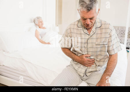 Suffering senior man holding his belly Stock Photo