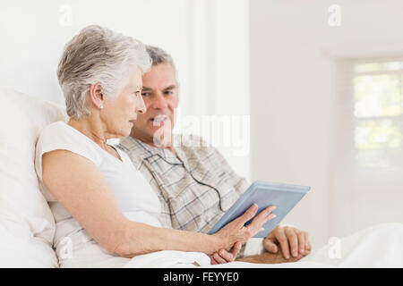 Senior couple using tablet on bed Stock Photo