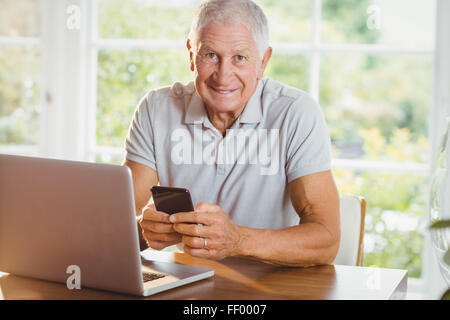 Senior man using his laptop and smartphone Stock Photo
