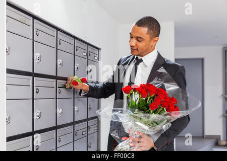 Lover boy puts roses in the letter box of the beloved Stock Photo