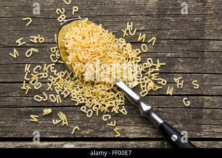 alphabet pasta in spoon on old wooden table Stock Photo