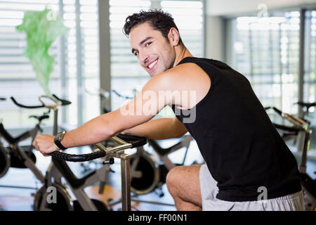 Smiling man using exercise bike Stock Photo