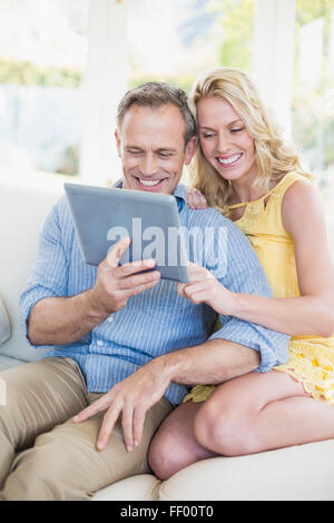Happy couple using tablet on the sofa Stock Photo