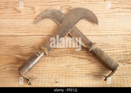 Two dated and used billhooks on wooden background Stock Photo