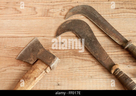 dated and used cleaver and two billhooks on wooden background Stock Photo