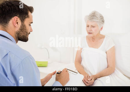 Home nurse listening to elderly woman and writing on clipboard Stock Photo