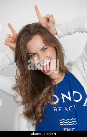 Happy woman in bunny ears with toy carrot on blue background. Easter ...