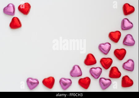 Chocolate heart shapes arranged on an isolated white background to make a frame with copy space. red and pink love heart candy. Stock Photo