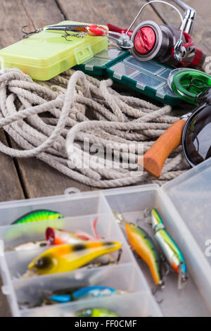 fishing tackles and baits in storage boxes with white cord and tools Stock Photo