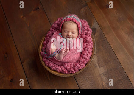 Smiling Newborn Baby Girl Sleeping in a Little, Wooden Bowl Stock Photo