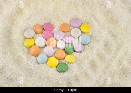 colorful bonbons arranged to make a heart in sugar Stock Photo