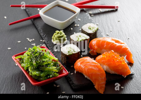 sushi and green seaweed salad on a slate table. Stock Photo