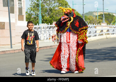 Traditional masked cultural figure VEJIGANTE and kid during the carnival in Ponce. Puerto Rico. US territory. February 2016 Stock Photo