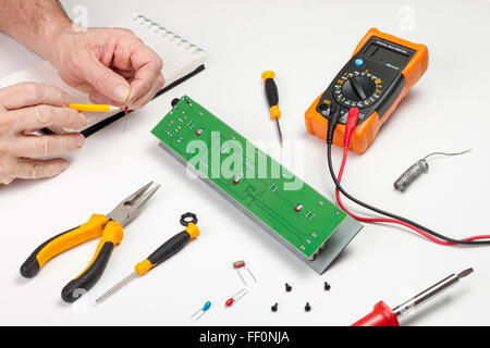 Electronics engineer at his workbench checking the value of a resistor Stock Photo