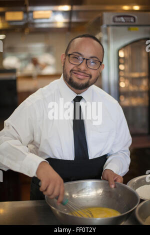 Mixed race chef with down syndrome cooking in restaurant Stock Photo