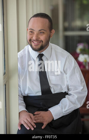 Mixed race server with down syndrome smiling in restaurant Stock Photo