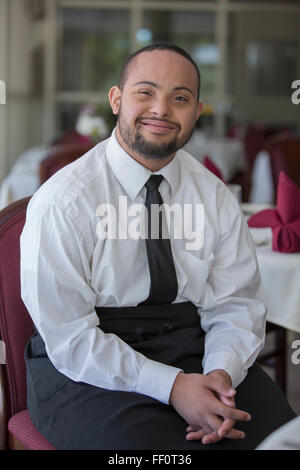 Mixed race server with down syndrome smiling in restaurant Stock Photo
