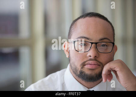 Mixed race man with down syndrome resting chin in hands Stock Photo