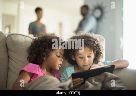 Sisters using digital tablet on sofa Stock Photo