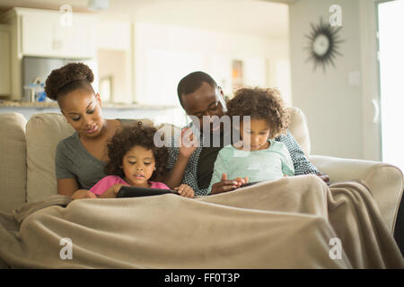Family using digital tablets on sofa Stock Photo