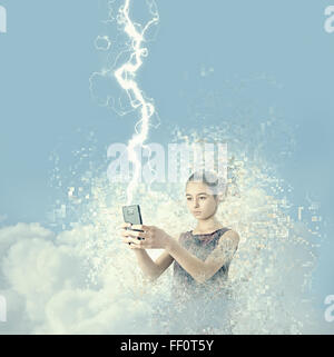 Mixed race girl holding cell phone in lightning Stock Photo