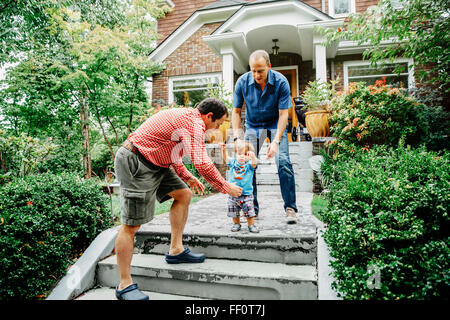 Gay fathers and baby son on steps Stock Photo