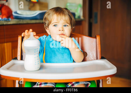 Mixed race baby boy drinking bottle in high chair Stock Photo