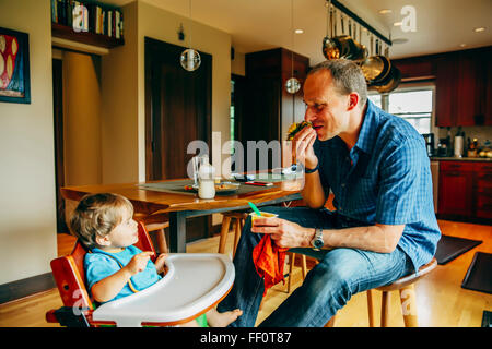 Father feeding baby son in high chair Stock Photo