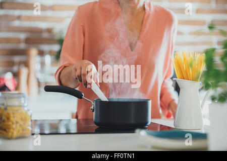 Older Caucasian woman cooking in kitchen Stock Photo