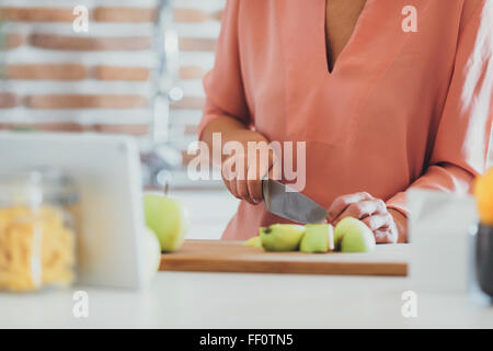 Older Caucasian woman cutting apples in kitchen Stock Photo