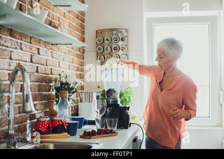 Older Caucasian woman making smoothie in kitchen Stock Photo