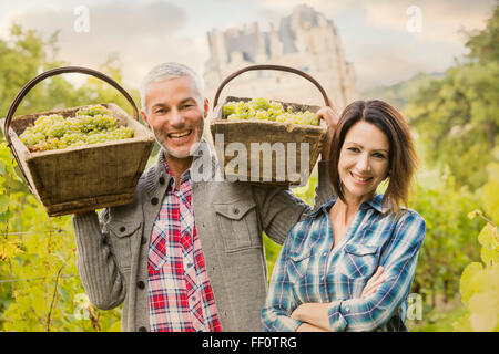 Caucasian farmers carrying grapes in vineyard Stock Photo
