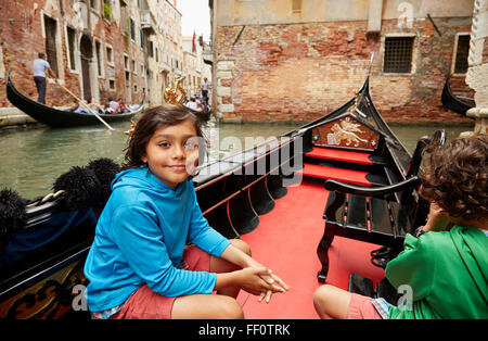 Boy sitting in gondola on Venice canal, Veneto, Italy Stock Photo