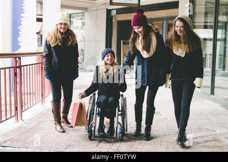 Girls walking and using wheelchair on sidewalk