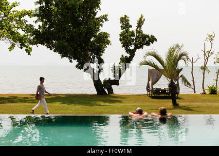 Couple swimming in luxury pool near ocean Stock Photo